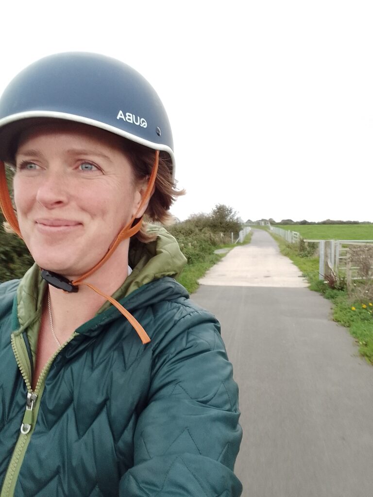 Me, a 41 year old woman with a smile on her face and a cycle helmet on my head. Cycling down a quiet, rural cycle path