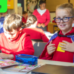 Primary school children learning about climate change. They are wearing makeshift hero capes. Overlaid is the Big Give/Earth Raise logo