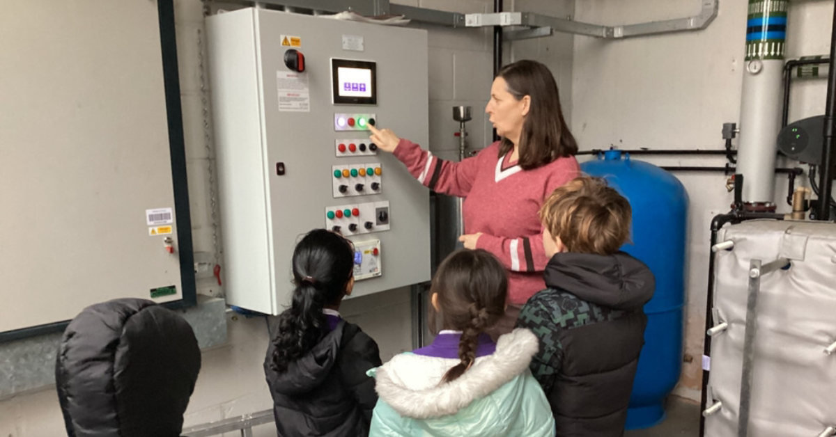 A primary school headteacher giving pupils a tour of the school's boiler room.